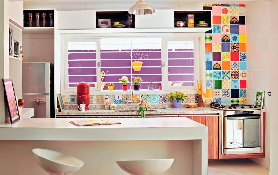 Os arm&aacute;rios sob a pia exibem laminado no padr&atilde;o madeira. Na face externa, o conjunto recebeu tinta branca e, por dentro, cor p&uacute;rpura. Azulejos: o mosaico acima da pia e atr&aacute;s do fog&atilde;o leva pe&ccedil;as antigas. Projeto de Ana Maria Mouawad Queiroga.