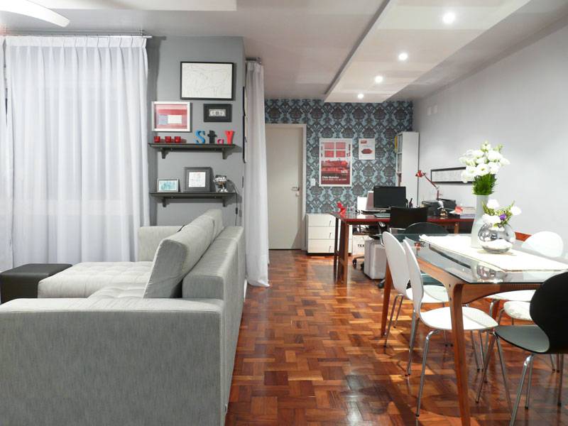 Integrar sala de estar, jantar, escrit&oacute;rio e cozinha em um s&oacute; ambiente n&atilde;o &eacute; f&aacute;cil. Neste espa&ccedil;o, de 42 m&sup2;, projetado pela arquiteta Thais Lenzi Bressiani, um dos desafios foi zonear bem cada &aacute;rea, para que as fun&ccedil;&otilde;es n&atilde;o se misturassem. Para isso, ela procurou harmonizar os materiais e acabamentos, trabalhando sempre as cores cinza, azul e vermelho.
