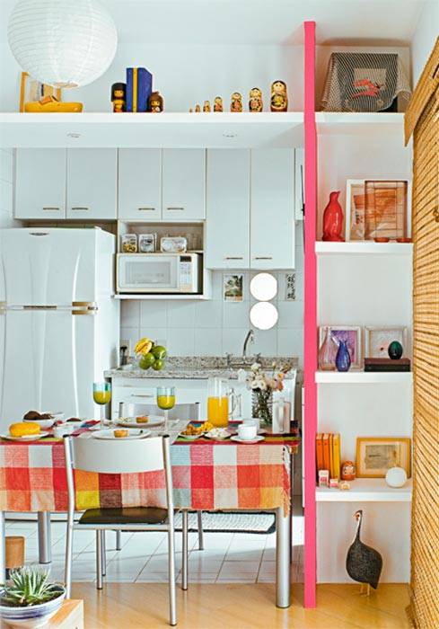 O v&atilde;o entre a sala e a cozinha veio abaixo e foi emoldurado com prateleiras de gesso no alto e em uma das laterais - nesta, est&atilde;o apoiados em um painel pintado de rosa-fosco. Dois espelhos redondos foram colados nos azulejos sobre a pia.