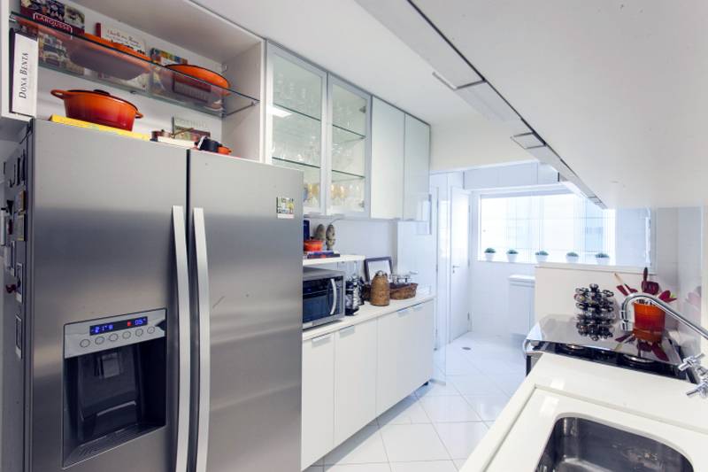 Neste projeto de Pereira Reade, a cozinha se prolonga at&eacute; a &aacute;rea de servi&ccedil;o, que ocupa todo o espa&ccedil;o do fundo. Para aproveitar a parede lateral inteira, uma marcenaria sob medida ocupa todo o espa&ccedil;o e abriga a geladeira, o microondas e m&aacute;quina de caf&eacute;.