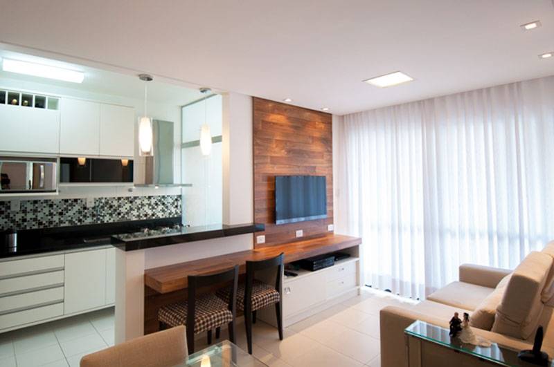 Em um apartamento pequeno, projetado pela arquiteta Maristela Bernal, o espa&ccedil;o de 14,5 m&sup2; precisou multiplicar as fun&ccedil;&otilde;es. Al&eacute;m de sala de estar, home theather, sala de jantar e cozinha, o ambiente ganhou elementos estrat&eacute;gicos, como o balc&atilde;o, que serve para servir as refei&ccedil;&otilde;es e tamb&eacute;m para trabalhar com o notebook.