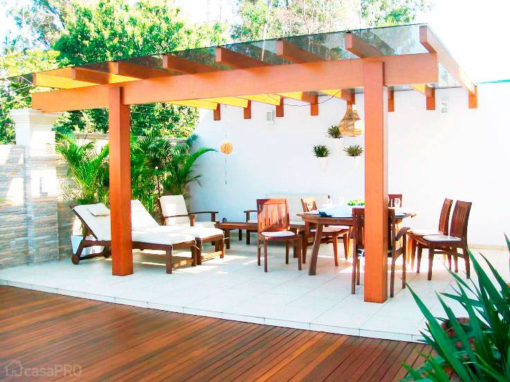 Pergolado feito de madeira com cobertura de vidro laminado fum&ecirc; e deck do mesmo material. Projeto de Alessanara Maioli.