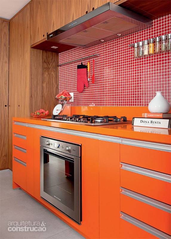 Antes moradora de um apartamento neutro, a dona desta resid&ecirc;ncia queria se livrar da monotonia. O tampo de Silestone (tonalidade naranja cool, fornecida pela Itaarte) estabeleceu o ponto de partida para o projeto, que estendeu a mesma cor &agrave; marcenaria. &ldquo;O c&ocirc;modo n&atilde;o tem ilumina&ccedil;&atilde;o direta, e este matiz foi uma maneira de deix&aacute;-lo mais vibrante&rdquo;, explica o arquiteto Maicon Antoniolli. Na parede, pastilhas de vidro (Colormix, ref. D40) completam a paleta quente.