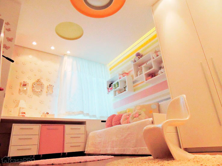 O quarto da menina de 3 anos recebeu cores alegres que, além de fugir dos tons bebê, permite ser utilizado pela menina até a adolescência. Na parede da janela, as arquitetas Jane Lima e Giovanna Brigatti aplicaram flores de MDF pintadas de branco e espelhos com molduras rebuscadas.