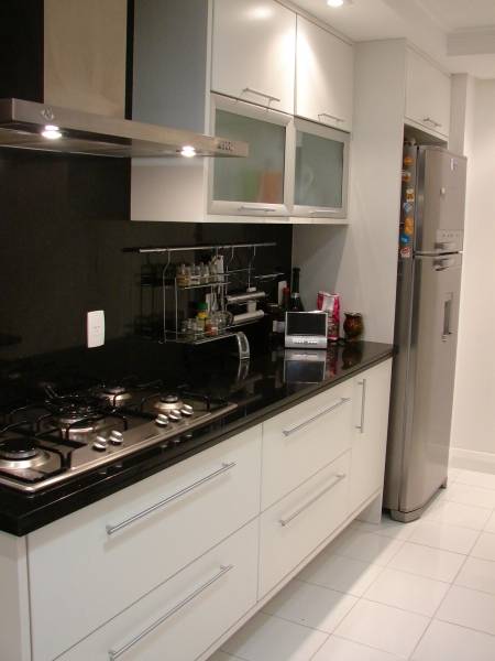 Prolongar a pedra da bancada at&eacute; a parede foi a op&ccedil;&atilde;o de L&iacute;via Gobetti para esta cozinha. Para n&atilde;o pesar nas cores, o resto do ambiente &eacute; branco.