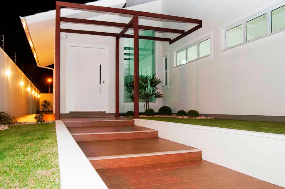 Resid&ecirc;ncia de alvenaria com pergolado de madeira na entrada. Projeto de Paula Corr&ecirc;a Pereira.