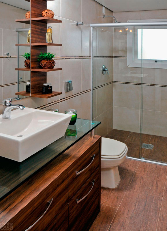 Com um estilo mais r&uacute;stico, este banheiro recebeu piso de porcelanato que imita madeira de demoli&ccedil;&atilde;o. Faixinhas de pedra contornam as paredes e se harmonizam com o porcelanato bege. A marcenaria de MDF recebeu acabamento de laminado melam&iacute;nico no padr&atilde;o madeira. Projeto de Let&iacute;cia Laurino Almeida.