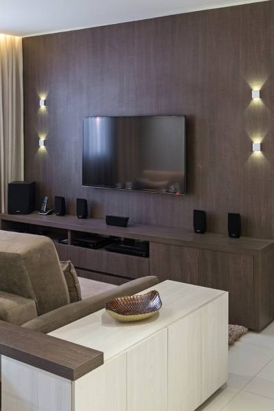 O home theater recebe um grande painel de madeira escura e um projeto luminot&eacute;cnico digno de cinema, assinado por Dessine. Projeto de Karla Amaral Madrilis.