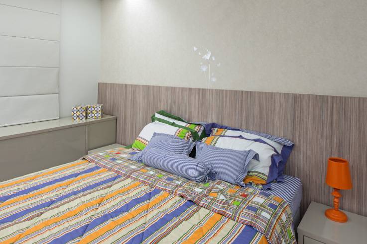 A su&iacute;te das moradoras tem cabeceira da cama em madeira, al&eacute;m de toques coloridos no jogo de cama para trazer alegria e vida ao espa&ccedil;o. Projeto de Karla Amaral Madrilis.