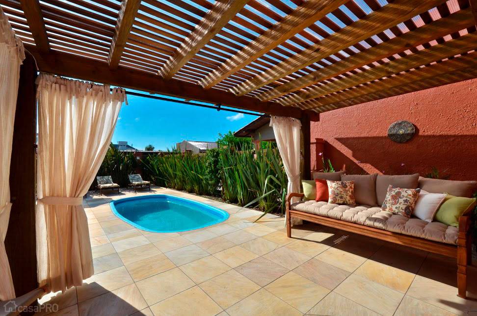 Com a cria&ccedil;&atilde;o do pergolado e da piscina foi poss&iacute;vel prolongar a &aacute;rea de lazer dessa resid&ecirc;ncia localizada no litoral norte ga&uacute;cho. O brise de madeira usado na cobertura e as cortinas deixam o ambiente sombreado. Projeto de Luciana Stefani.