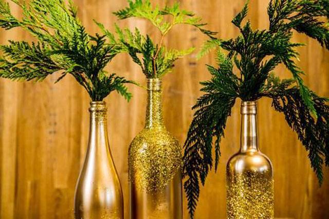 A decora&ccedil;&atilde;o de Natal dourada est&aacute; com tudo! Pinte suas garrafas com tinta e glitter e adicione ramos. Essa decora&ccedil;&atilde;o funciona tamb&eacute;m para o ano novo.