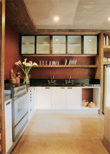 26 m&sup2;: Genuinamente mineira, esta cozinha ostenta o tradicional vermelh&atilde;o, revestimento composto de cimento queimado e pigmentos naturais. Comum no piso das casas de Minas Gerais, onde fica a moradia, ele aqui cobre as paredes. E destaca o ambiente, j&aacute; que os demais c&ocirc;modos s&atilde;o brancos, diz o arquiteto Marcelo Alvarenga, s&oacute;cio de Jos&eacute; Ricardo Fois. T&iacute;pica do estilo solicitado pela propriet&aacute;ria, a madeira de demoli&ccedil;&atilde;o comp&otilde;e arm&aacute;rios e emoldura o teto, onde disfar&ccedil;a imperfei&ccedil;&otilde;es da laje de concreto. Feito de ripas de madeira sobrepostas a uma estrutura de ferro chumbada na alvenaria, o escorredor de pratos deixa a pia livre.