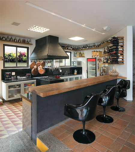 19 m&sup2;: Uma casa em volta da cozinha foi o pedido do conceituado chef mineiro Cantidio Lanna ao casal de arquitetos Joana e Tom&aacute;s Anastasia, de Belo Horizonte. Ele tamb&eacute;m exigiu lugar para fog&atilde;o e coifa industriais e para sua cole&ccedil;&atilde;o de conhaques, al&eacute;m de um forno de pizza. Rebaixado 20 cm em rela&ccedil;&atilde;o &agrave; sala, o piso de ladrilhos hidr&aacute;ulicos permite que o cozinheiro trabalhe de p&eacute;, no mesmo n&iacute;vel dos amigos, acomodados em confort&aacute;veis cadeiras com encosto. Assim a bancada de 70 cm de altura atende aos dois lados. Se o piso fosse nivelado, o balc&atilde;o teria de ter 90 cm, medida ideal para quem prepara a comida de p&eacute;, e os convidados precisariam se sentar em banquetas de bar, mais altas, diz Tom&aacute;s.
