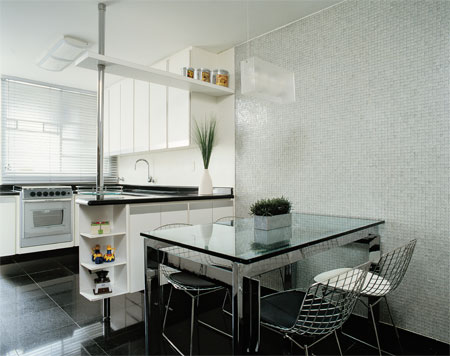 13 m&sup2;: Sobrepor acabamentos foi a maneira mais r&aacute;pida de modernizar a cozinha sem grandes quebradeiras. Os moradores permaneceram no apartamento durante a reforma, lembra a arquiteta paulista Karina Korn. No piso, placas de granito preto s&atilde;o gabriel com 1 cm de espessura cobriram a cer&acirc;mica existente, enquanto folhas de laminado branco esconderam os azulejos das paredes. Menos na copa: como a vontade era setorizar os ambientes, nessa &aacute;rea, clientes e arquiteta preferiram pastilhas de vidro transparentes, que s&oacute; puderam ser colocadas ap&oacute;s a remo&ccedil;&atilde;o dos azulejos. A divis&atilde;o &eacute; refor&ccedil;ada por um m&oacute;vel suspenso com 30 cm de profundidade  medida ideal para as lou&ccedil;as ali guardadas.
