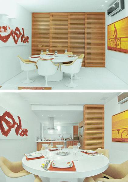 A porta de correr com quatro folhas, feita de peroba-mica, integra as diferentes &aacute;reas deste apartamento. Aberta, ela permite o acesso &agrave; cozinha, onde se encontra a bancada de peroba com tampo de aglomerado branco.