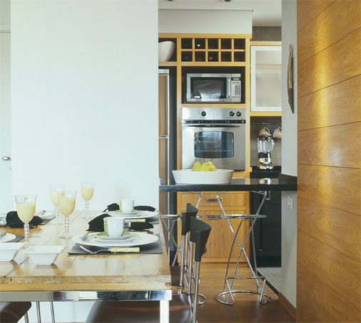 Esta &eacute; uma uni&atilde;o diferente. No apartamento de 81 m&sup2; do arquiteto Bernard Leroux, a parede que separa a cozinha da sala possui um pilar estrutural. A integra&ccedil;&atilde;o das &aacute;reas na reforma foi feita com um v&atilde;o que n&atilde;o influencia na estrutura. O balc&atilde;o multiuso de granito preto serve tanto para servir convidados quanto para refei&ccedil;&otilde;es r&aacute;pidas.