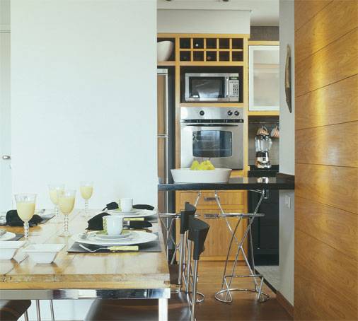 Esta &eacute; uma uni&atilde;o diferente. No apartamento de 81 m&sup2; do arquiteto Bernard Leroux, a parede que separa a cozinha da sala possui um pilar estrutural. A integra&ccedil;&atilde;o das &aacute;reas na reforma foi feita com um v&atilde;o que n&atilde;o influencia na estrutura. O balc&atilde;o multiuso de granito preto serve tanto para servir convidados quanto para refei&ccedil;&otilde;es r&aacute;pidas.