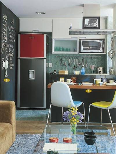 Apenas um balc&atilde;o preto separa a sala da cozinha, neste apartamento de 68 m&sup2;. Esta &eacute; a cor base da decora&ccedil;&atilde;o, que ajuda na integra&ccedil;&atilde;o por estar nos dois ambientes. O casal de publicit&aacute;rios Fernando e Melissa Alves utilizaram detalhes coloridos para descontrair o espa&ccedil;o. Projeto dos arquitetos Ricardo Miura e Carla Yasuda.