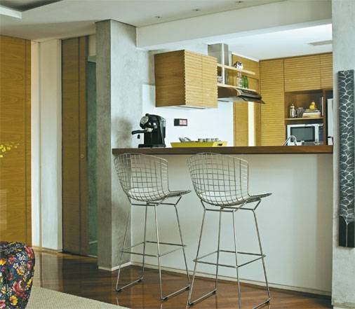 Neste apartamento de 80 m&sup2;, a madeira prevalece em todos ambientes, unificando-os. A integra&ccedil;&atilde;o da cozinha com a sala fica por conta da bancada de ip&ecirc;, que disponibiliza ainda dois lugares para refei&ccedil;&otilde;es. As arquitetas Adriana Cocchiarali e Isabela Jock Piva assinam esta reforma.