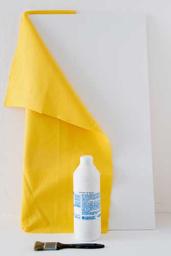 Usando a trincha, passe a cola na base do mural e aplique o feltro cobrindo t...