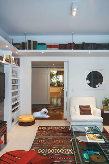 Fixada pr&oacute;xima ao teto, a prateleira suspensa circunda a sala &iacute;ntima da cas...