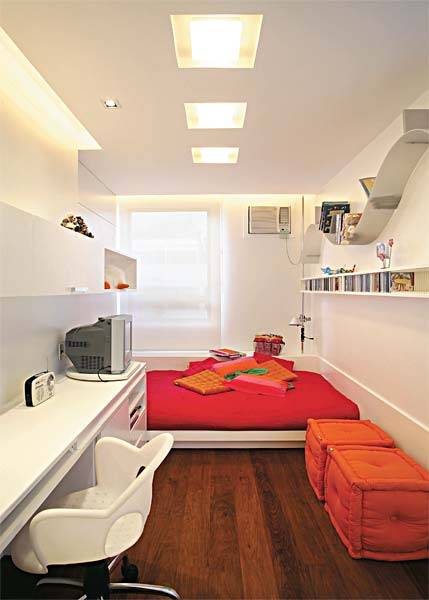 A jovem estudante queria que seu quarto, de 14 m&sup2;, tivesse um estilo moderno. Para atender o pedido, os arquitetos Paula Neder e Alexandre Monteiro optaram por um futon bem baixo. Seguindo a linha do p&eacute; da cama, colocaram uma escrivaninha para estudos e TV. Na mesma parede, fixaram um arm&aacute;rio suspenso laqueado, para livros e objetos decorativos, e, na outra, bem em frente, distribu&iacute;ram prateleiras delicadas com profundidade e altura das caixas de CDs. A cor branca predominante &eacute; quebrada pelos tons vibrantes do enxoval e pelos pufes. O piso de peroba <span>&mdash;&nbsp;</span>com r&eacute;guas de 20 cm de largura <span>&mdash; </span>&eacute; t&atilde;o bonito que dispensou tapete.