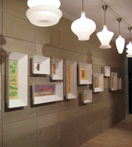 No corredor, cole&ccedil;&atilde;o de quadros com molduras volumosas e uma s&eacute;rie de lumi...