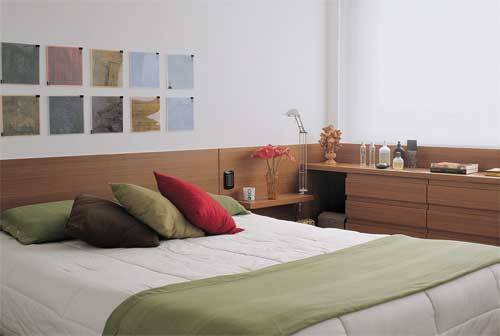 O repouso no escurinho do quarto &eacute; garantido pelas cortinas duplas: uma persiana de tela solar e outra blecaute (Luxaflex), emolduradas em uma estrutura de madeira laqueada. A textura da madeira aquece o quarto: o painel de imbuia-linheiro (90 cm de altura) serve de cabeceira e alcan&ccedil;a o arm&aacute;rio sob a janela. Para manter a unidade visual, as gavetas n&atilde;o t&ecirc;m puxadores.