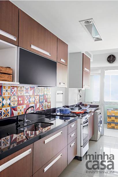 Os moradores, os engenheiros Giselle Farias e Fernando Nunes, elegeram o padr&atilde;o amadeirado noce para o acabamento da marcenaria, aquecendo a decora&ccedil;&atilde;o, valorizada ainda mais com a parceria dos artesanais ladrilhos hidr&aacute;ulicos (Portal da Barra).