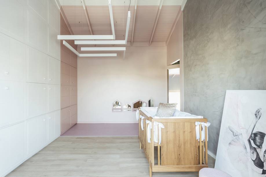 O minimalismo aliado a tons past&eacute;is sugere um ambiente clean, livre e amplo o bastante para praticar bal&eacute; e brincar. As &aacute;reas foram sutilmente delimitadas, apenas com a pintura em tom ros&eacute;. A parte funcional do dormit&oacute;rio fica escondida sob m&oacute;dulos 3D na parede. Outro destaque &eacute; a presen&ccedil;a contempor&acirc;nea do ciment&iacute;cio na parede e da lumin&aacute;ria geom&eacute;trica. Ninar da Beb&ecirc; - Natalia Kuhn e Danixa Kuhn. CASACOR Rio Grande do Sul.