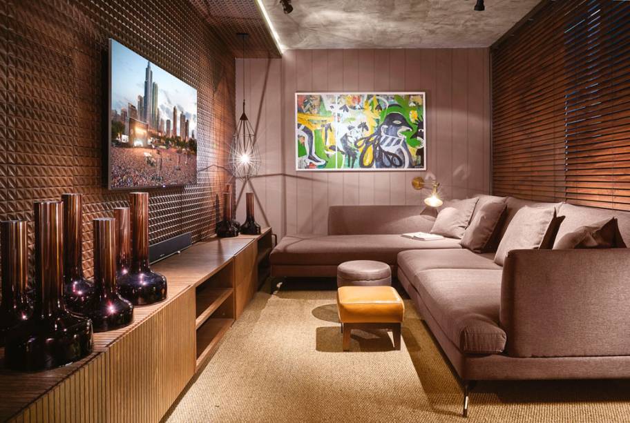 Tonalidades s&oacute;brias e amadeiradas predominam no projeto das arquitetas Larissa Maffra e Marina Bastos, que reservaram as cores mais chamativas para os complementos e as obras de arte. O sof&aacute; com chaise garante o conforto com suas dimens&otilde;es generosas. Para aprimorar a qualidade ac&uacute;stica do espa&ccedil;o, a estrat&eacute;gia foi sobrepor dois tapetes. O projeto luminot&eacute;cnico &eacute; pontual e flex&iacute;vel, com destaque para o pendente da designer holandesa Sylvie Meuffels.