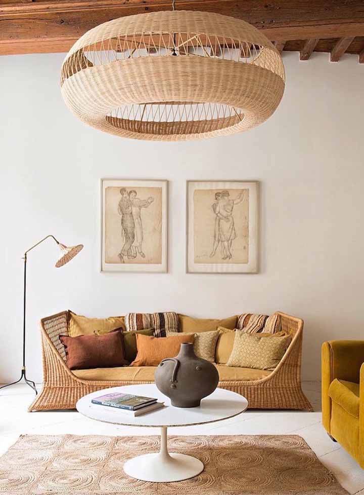 Os tons terrosos e os m&oacute;veis com fibras naturais chamam a aten&ccedil;&atilde;o nesta sala. O teto em madeira refor&ccedil;a o aspecto r&uacute;stico do espa&ccedil;o e combinado a enorme lumin&aacute;ria em vime confere personalidade. A luz natural abundante faz a sala ficar ainda mais convidativa.