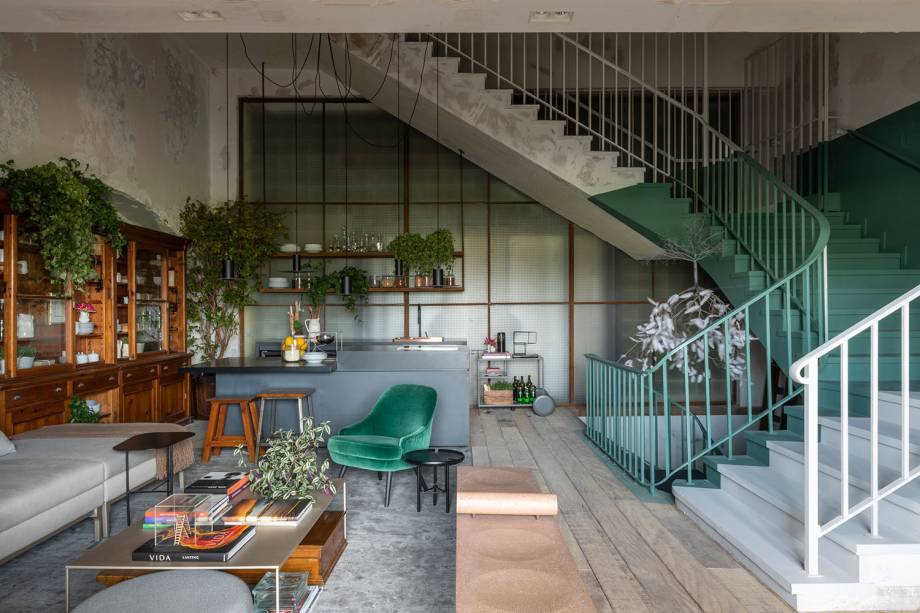 A est&eacute;tica r&uacute;stica e desgastada da constru&ccedil;&atilde;o original foi ressignificada, produzindo uma atmosfera criativa e convidativa na Cozinha Matriz da Triart Arquitetura na CASACOR S&atilde;o Paulo. O mobili&aacute;rio &eacute; ecl&eacute;tico e explora a madeira e os tons de verde. Nas escadarias, o color block valoriza as formas e destaca a escultura em formato de &aacute;rvore, do artista cubano Jorge Mayet.