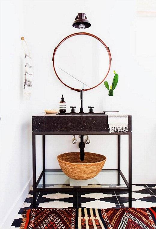 Espelho rendondo, lumin&aacute;ria retr&ocirc;, e piso e tapete estampados se encontram no d&eacute;cor deste lavabo.