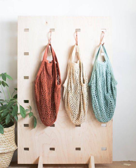 Quando vazio, o painel de madeira funciona como objeto de decora&ccedil;&atilde;o, mas basta adicionar alguns ganchos metalizados e pronto, uma &oacute;tima op&ccedil;&atilde;o para guardar as ecobags.