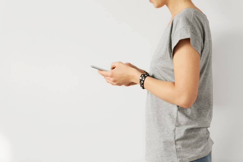 People, modern technologies and gadgets. Social networks addiction. Cropped side view of stylish Caucasian female typing on smartphone, surfing internet, commenting posts and messaging friends online People, modern technologies and gadgets. Social networks addiction. Cropped side view of stylish Caucasian female typing on smartphone, surfing internet, commenting posts and messaging friends online