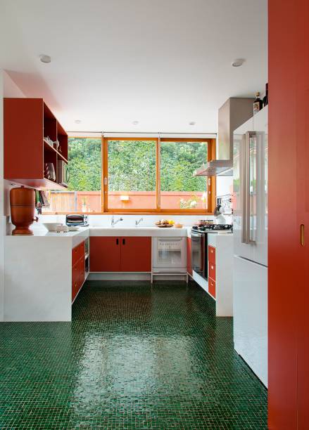 A vista para a rua guiou o projeto desta cozinha, feita pelo escrit&oacute;rio Andr&eacute; Vainer Arquitetos. O vermelho e o verde do exterior foram incorporados na ambienta&ccedil;&atilde;o, o primeiro na marcenaria sob medida e o segundo no piso em mosaico