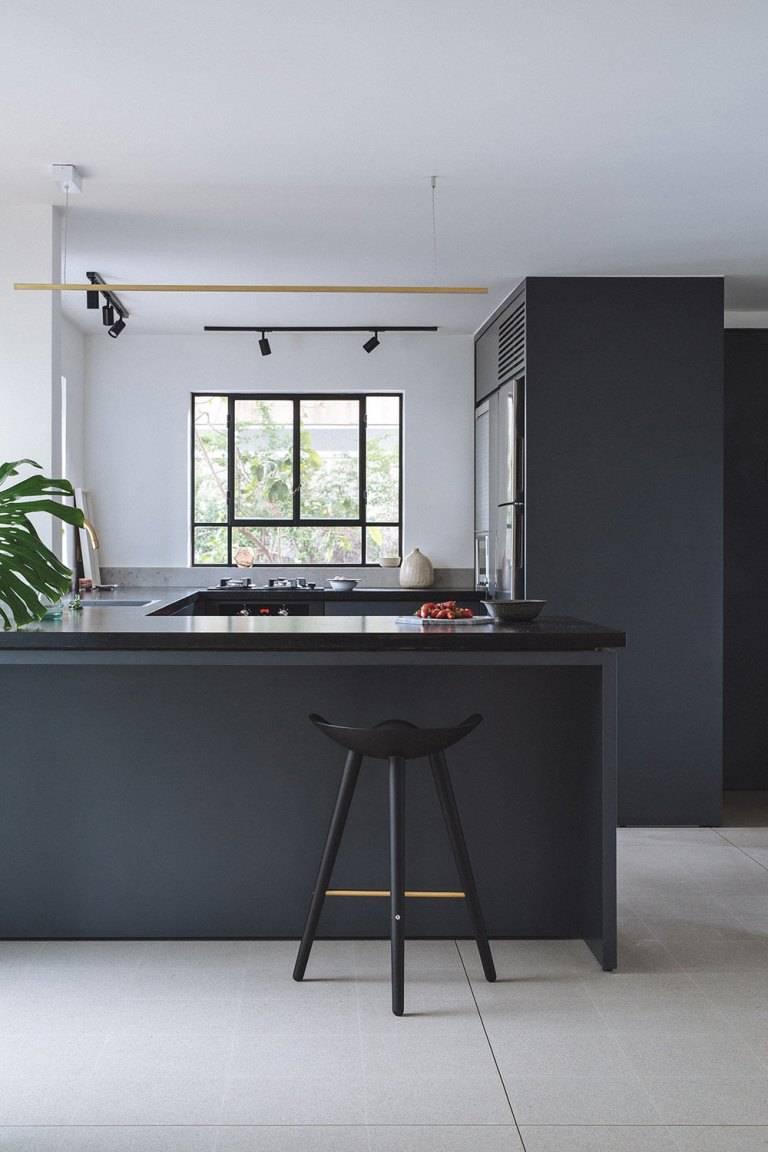 Reformada pelo THISISIT Architecture & Design, esta cozinha ganhou revestimentos grafite e uma bancada de pedra preta. O grande toque especial do d&eacute;cor &eacute; a presen&ccedil;a de detalhes em lat&atilde;o em bronze e dourado - como na torneira, nos lustres e na banqueta. A presen&ccedil;a da costela-de-Ad&atilde;o d&aacute; mais vida e cor ao espa&ccedil;o