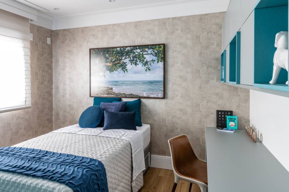 Uma das suítes do apartamento foi direcionada aos hospedes do casal: um quarto aconchegante e despojado, com tons de azul e cinza. O papel de parede usado lembra cimento queimado e o quadro com paisagem de praia (Gigi Monteiro) traz tranquilidade ao ambiente.