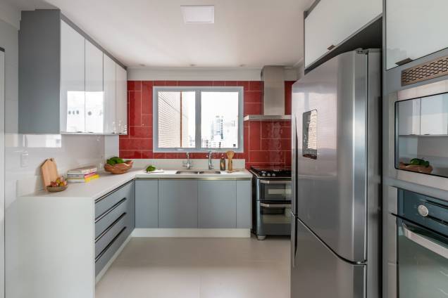 Na cozinha, a arquiteta adicionou um toque de cor com o revestimento vermelho na parede acima da bancada. Na cozinha, a arquiteta adicionou um toque de cor com o revestimento vermelho na parede acima da bancada.