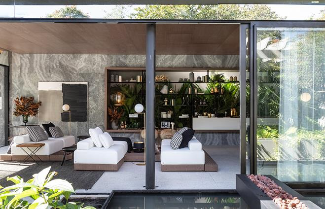 No ambiente <strong>Casa Grão</strong>, do escritório Très Arquitetura, a estante compõe toda a parede principal. Da base ao topo, o móvel imponente abriga os mais diversos objetos, como livros, itens decorativos e plantas.