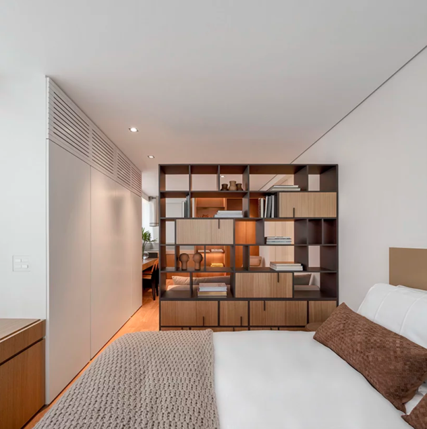 Uma prateleira de metal e madeira separa o quarto da sala de estar, que também pode ser usada como escritório ou sala de jantar. Uma prateleira de metal e madeira separa o quarto da sala de estar, que também pode ser usada como escritório ou sala de jantar.