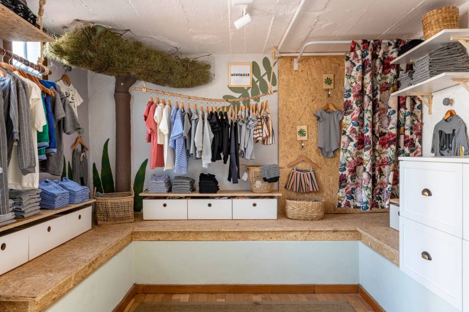 Lojinha - Ayla de Barros, da Dearq, e Carlos Lima, da Marcenaria Lima. Instalada no porão da casa, a lojinha preserva características originais do imóvel, como os tijolinhos, os baldrames e o piso de parquê em madeira. O handmade é protagonista neste ambiente, vide os cabideiros feitos de galhos, a escada de bambu usada como expositor e os vasos pendurados em hangers feitos de macramê com corda de algodão.