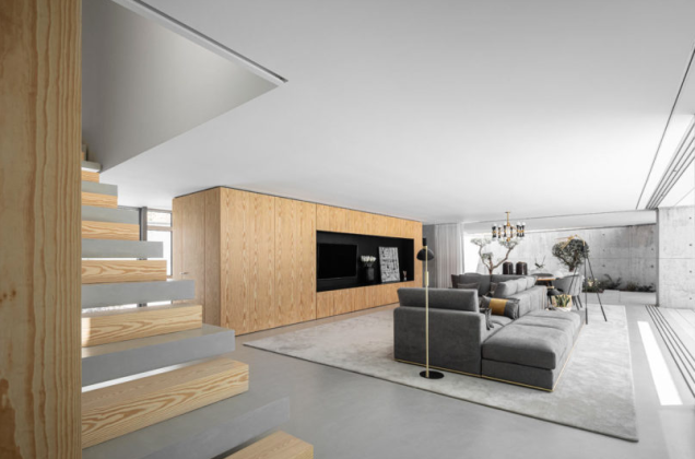 A cor cinza do concreto ao ar livre continua no interior, com o piso, o mobiliário e as escadas alternadas na escada aberta. Os cinzas frios são complementados com detalhes de madeira natural usados por toda parte. A cor cinza do concreto ao ar livre continua no interior, com o piso, o mobiliário e as escadas alternadas na escada aberta. Os cinzas frios são complementados com detalhes de madeira natural usados por toda parte.