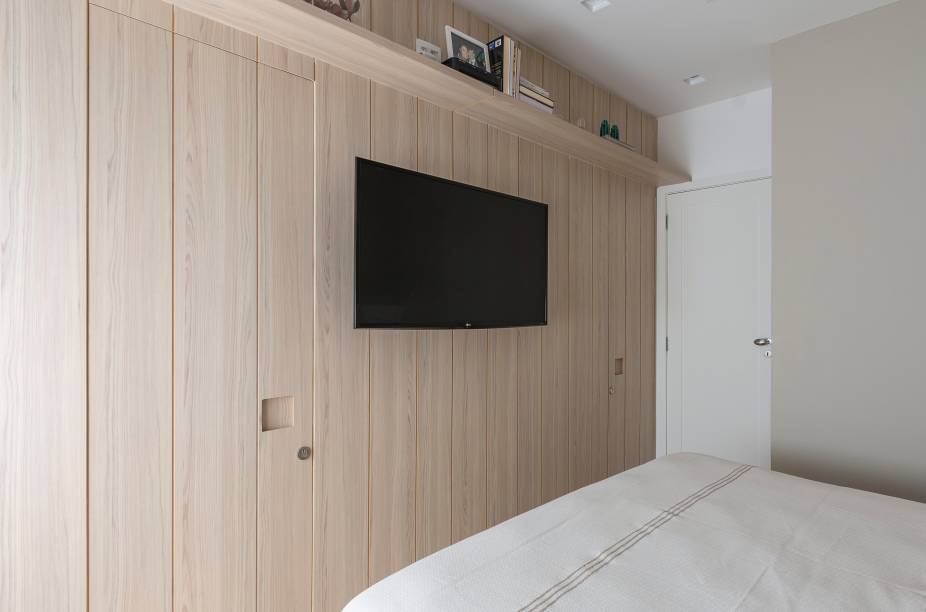 O painel em marcenaria de acabamento CIPRES, da Guararapes, esconde o banheiro da suíte e um pequeno closet, logo de entrada. O painel em marcenaria de acabamento CIPRES, da Guararapes, esconde o banheiro da suíte e um pequeno closet, logo de entrada.