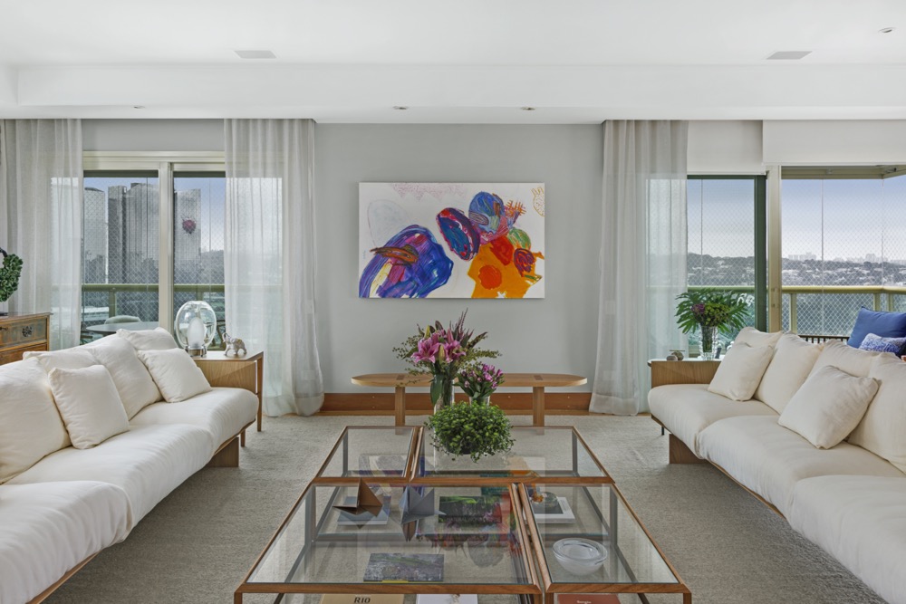 Sala integrada com sofás claros e quadro colorido na parede