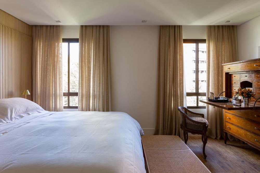 quarto com cortinas leves, madeira e móvel antigo