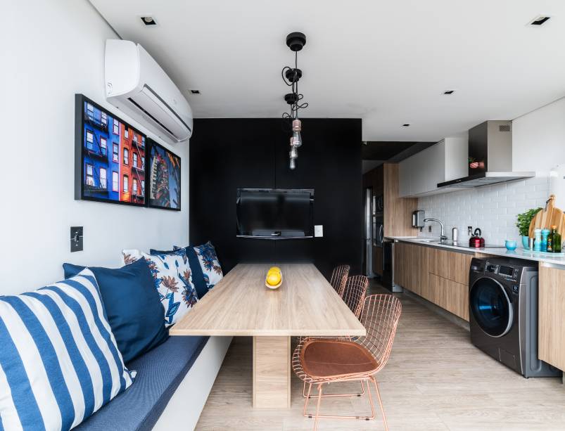 No projeto do apartamento da arquiteta Júlia Guadix, o canto alemão, colocado entre a cozinha e varanda, recebeu um banco baú branco com detalhes em azul e três cadeiras Bertoia em cobre. Os pendentes seguem o estilo industrial, predominante nos demais cômodos. A mesa de madeira complementou a composição No projeto do apartamento da arquiteta Júlia Guadix, o canto alemão, colocado entre a cozinha e varanda, recebeu um banco baú branco com detalhes em azul e três cadeiras Bertoia em cobre. Os pendentes seguem o estilo industrial, predominante nos demais cômodos. A mesa de madeira complementou a composição