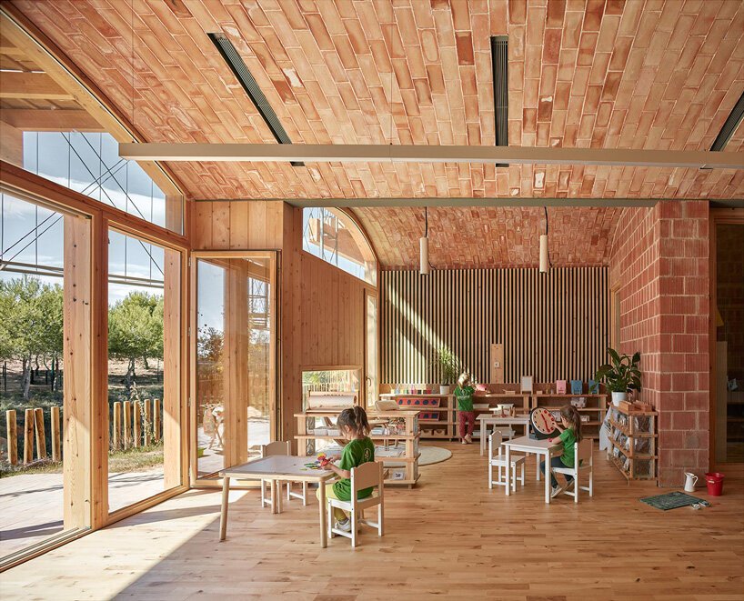 arquitetos-constroem-escola-montessouri-na-espanha-casa.com-10 Sala de aula ampla, com janelas e porta de vidro; mesas e