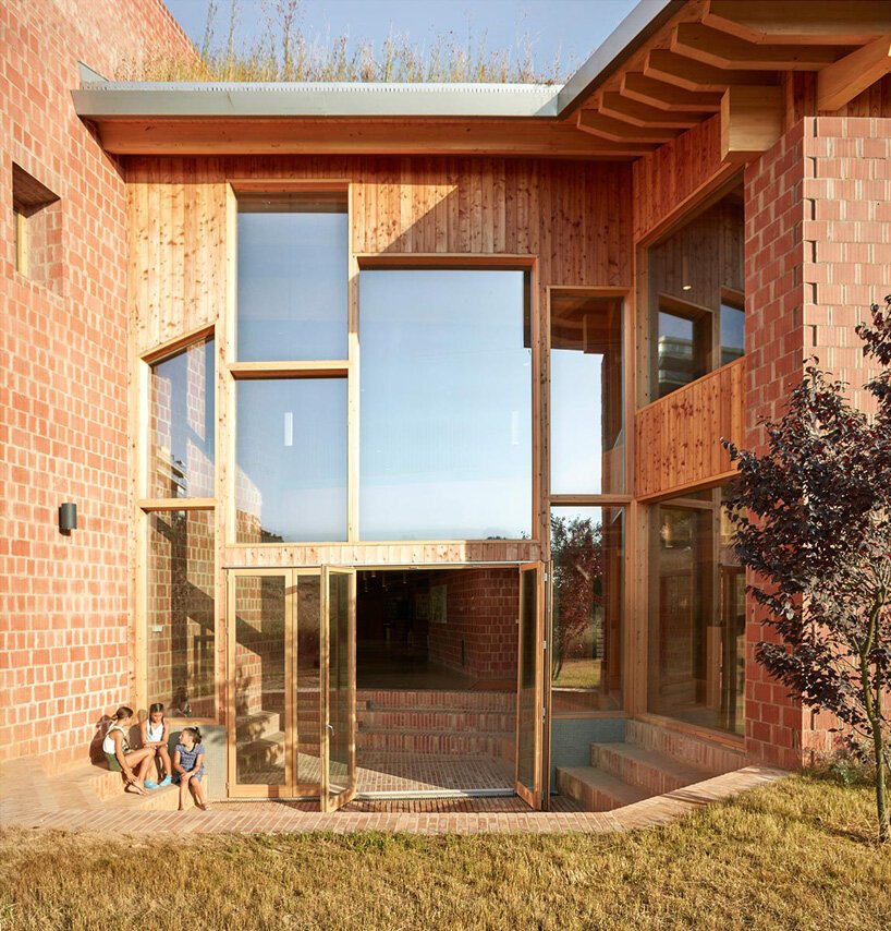 arquitetos-constroem-escola-montessouri-na-espanha-casa.com-5 Péd ireito triplo da escola com crianças brincando no pátio